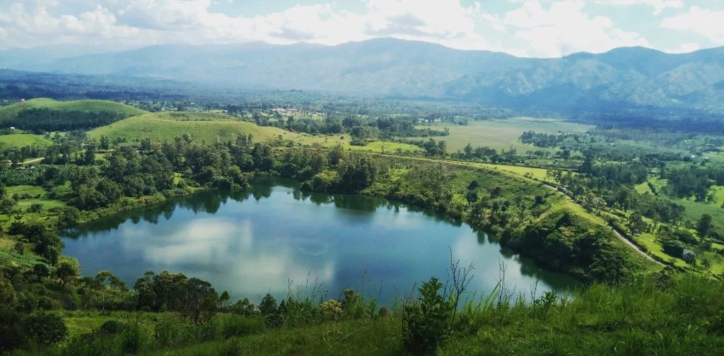 A green lake surrounded by cultivated hills